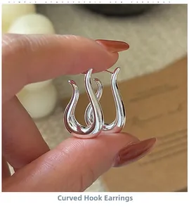 Macro detail of silver curved hook earrings with a polished finish and minimalist design
