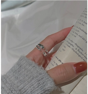 Detail of silver liquid metal ring with irregular texture worn on a hand holding a book