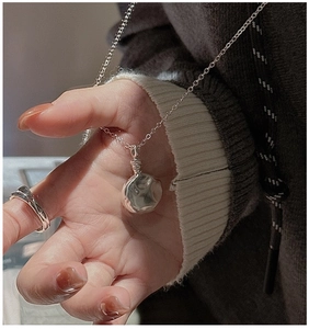 Nahaufnahme der S925 Sterling Silber Halskette mit gehämmerter Textur auf grauem Pullover