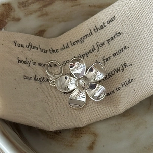 S925 sterling silver flower pendant with polished finish and vintage textile background