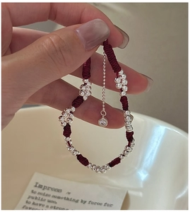 Detail of red woven bracelet with silver beads and sparkling zircon charm on a wrist