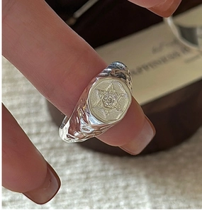 Macro shot of silver ring with hammered texture, hexagram engraving and a tiny diamond