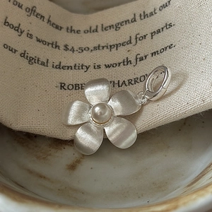 S925 sterling silver flower pendant with brushed texture and pearl on ceramic plate