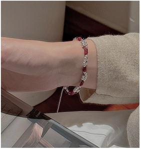 Close-up of red braided rope bracelet with silver beads on a model wearing knitwear