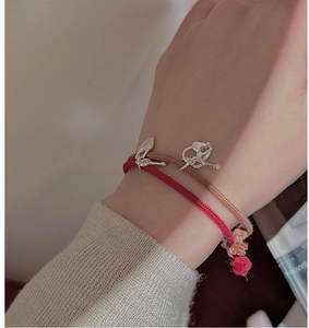 Detail of woven red and brown cord bracelets with silver heart lock and key charms
