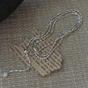 S925 silver beaded necklace with round zircon pendant on rustic linen and vintage book page