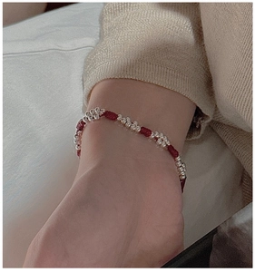 Detail of red braided cord bracelet with silver beads on wrist in soft lighting