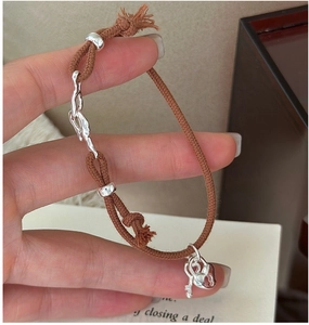 Detailed view of woven rope bracelet featuring a silver heart lock and key pendant