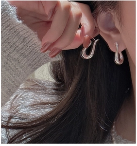 Close-up of elegant S925 sterling silver U-shaped earrings worn by a model with polished finish