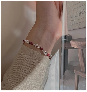 Close-up of a red woven rope bracelet with silver beads on a model's wrist