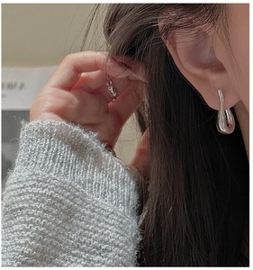 Close-up of polished S925 sterling silver water drop earrings worn by a model