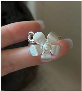 Macro view of S925 silver flower ring featuring matte texture and a pearl center