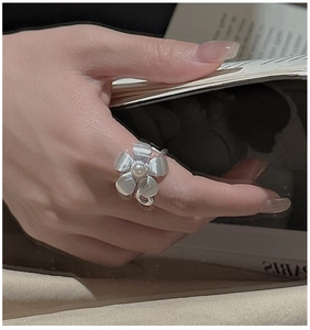 Detail of S925 silver flower ring with a white pearl on a vintage textured surface