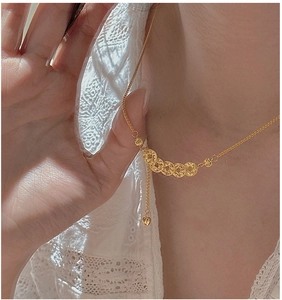 Detail of vintage gold coin necklace with interlocking rings and heart charm on model
