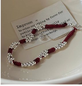 Macro shot of retro braided red rope bracelet with silver beads and zircon pendant