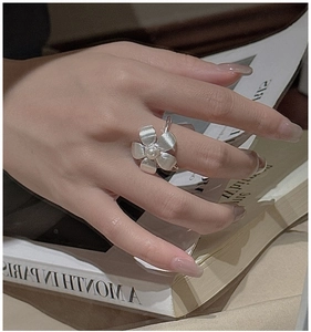Close-up of a vintage S925 silver flower ring with a pearl and brushed metal texture