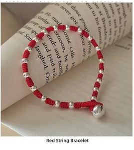 Close-up of handmade red braided cord bracelet with silver beads on a vintage book