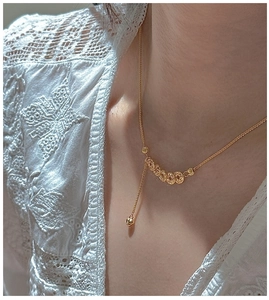 Detailed view of vintage gold necklace featuring intricate CNC round beads and a heart tassel