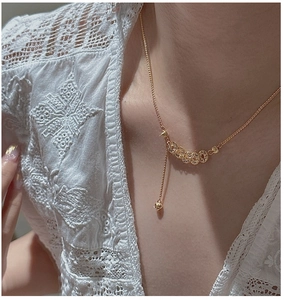 Close-up of gold Y-shaped coin pendant necklace with tassels on a female model