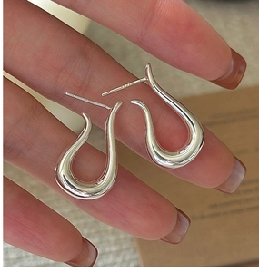 Macro shot of S925 sterling silver stamp on minimalist curved U-shaped hook earrings