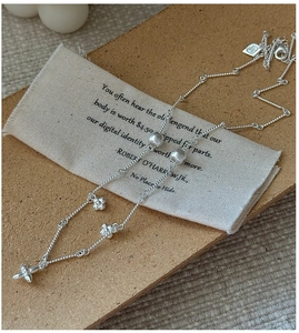 Detail of S925 silver necklace with textured rope chain and matte floral charms