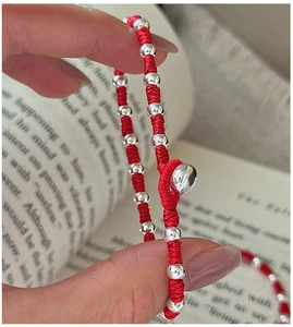 Macro view of hand-woven red rope bracelet with polished silver beads on a book