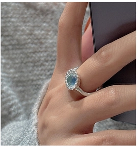 Dettaglio anello argento S925 con gemma blu su base a petalo lavorata a mano