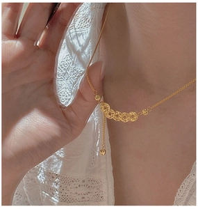 Close-up of gold necklace with five ancient coin pendants and small heart charm