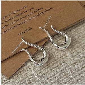 Macro shot of minimalist S925 sterling silver hook earrings with polished mirror finish