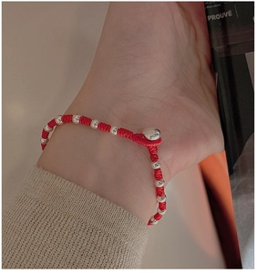 Close-up of handmade red braided bracelet with silver beads on a female wrist