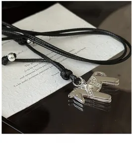 Gros plan du pendentif cheval argenté avec motifs d'étoiles sur cordon noir