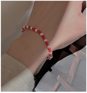 Close-up of woven red rope bracelet with S925 sterling silver beads on a model wrist