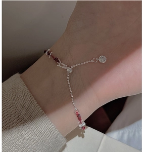 Détail du bracelet en cordon rouge tressé avec perles d'argent et un charmant zircon brillant