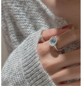 Dettaglio di un anello vintage in argento S925 con gemma blu su sfondo lavorato a maglia