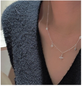 Detail of silver S925 flower pendant necklace on model with dark textured sweater