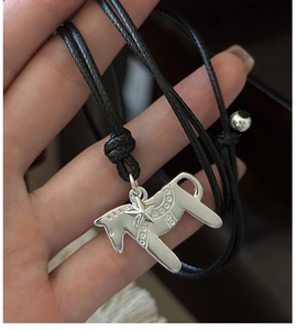 Gros plan du pendentif cheval en argent avec breloque étoile sur un collier en corde noir