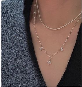 Close-up of layered S925 silver flower clover pendant necklace and sparkling tennis chain