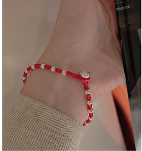 Macro shot of a red woven rope bracelet with silver beads worn on a wrist