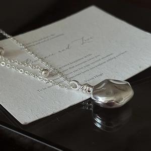 Minimalistische S925 Silberkette mit flüssigem Metallanhänger in Kieselsteinform auf Karte