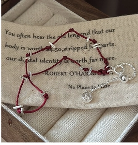 Détail du bracelet tressé rouge avec tubes en argent et pendentif en zircone clair