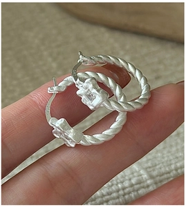Detail of S925 sterling silver twist hoop earring with a square zircon and matte finish
