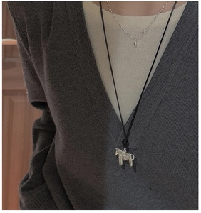 Colliers superposés avec pendentif cheval en argent S925 sur un pull en maille