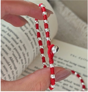 Detailed close-up of handmade red braided cord bracelet with polished silver beads