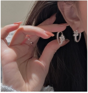 Close-up of twisted S925 sterling silver hoop earrings and minimalist ring on model