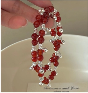 Detail of red agate bead bracelet with silver bells and charms on a woman's wrist