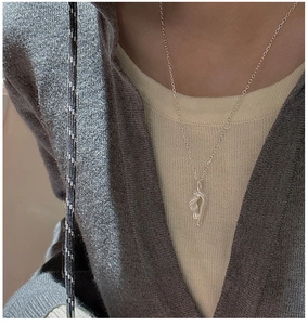 Close-up of minimalist S925 sterling silver necklace with abstract twisted pendant