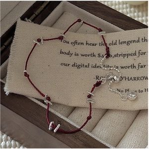 Détail du bracelet en corde rouge tressée avec barres argentées et chaîne zircon réglable