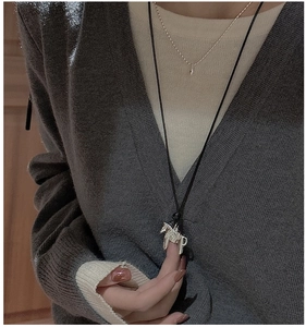 Détail macro d'un pendentif cheval en argent sur cordon noir porté par un modèle