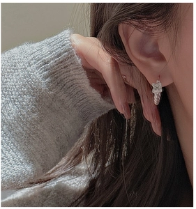 Close-up of S925 sterling silver twisted hoop earrings with square charm on model