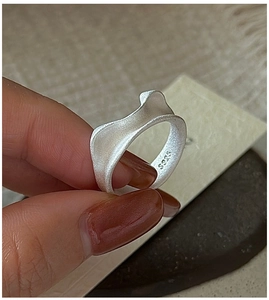 Close-up of matte S925 sterling silver ring featuring a wave texture and hallmark stamp